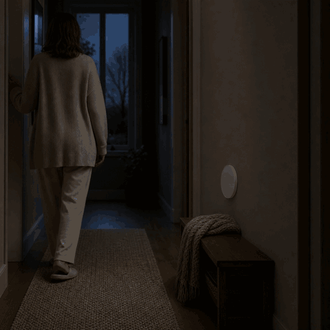 Woman walks into the dark hallway and the LumiBeam night light turns on via motion sensor