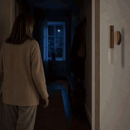 Woman walks through the dark hallway and the LumiWood wooden wall light switches on via motion sensor